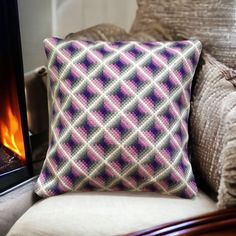 a purple and white pillow sitting on top of a couch next to a fire place