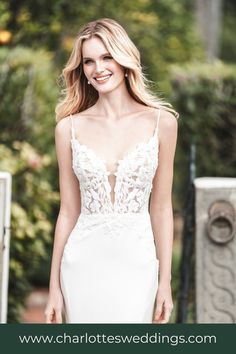 a woman in a white wedding dress smiling at the camera with her hand on her hip