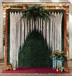 an outdoor ceremony with macrami and greenery draped over the altar, surrounded by red carpet