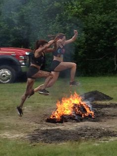 two people jumping in the air over a fire