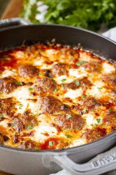 a close up of a casserole dish with meatballs and cheese on it