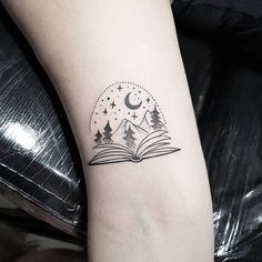 an open book tattoo on the arm with mountains and stars above it, under a crescent moon