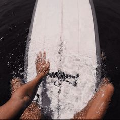 two people on a surfboard in the water with their feet propped up against the board