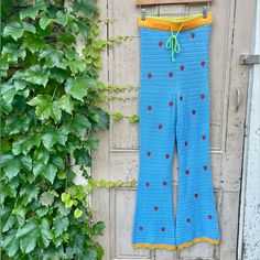 a pair of blue knitted pants hanging on a wall next to a green plant