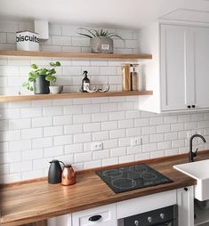 a kitchen with white cabinets and wooden counter tops, including a stove top oven next to a sink