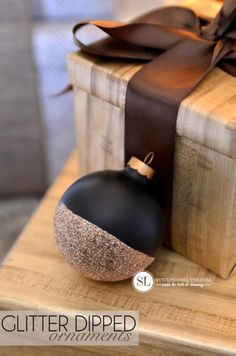 a black ornament sitting on top of a wooden box next to a brown ribbon