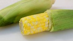 corn on the cob is sitting next to an ear of corn