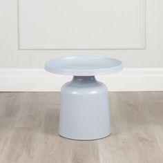 a white table sitting on top of a hard wood floor next to a wall in a room