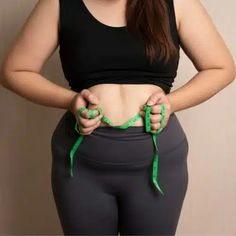 a woman in black top and grey pants with green string attached to her waist,