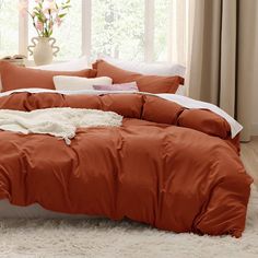 a bed with an orange comforter and white pillows