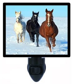 three horses running in the snow on a computer monitor with a camera attached to it