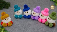 several small knitted snowmen sitting next to each other in front of a christmas tree