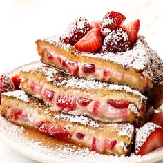 french toast with strawberries and powdered sugar on top is served on a white plate