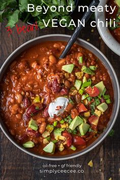 two bowls filled with chili, avocado and sour cream on top of a wooden table