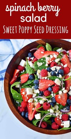 a salad with spinach, strawberries and feta cheese in a wooden bowl