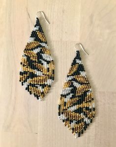 two pairs of beaded earrings sitting on top of a wooden table