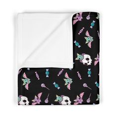 a black blanket with skulls and unicorns on it