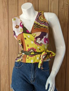 Found! 🔍 Super cool y2k sleeveless wrap top in bold 60s/70s inspired mixed prints and with a flattering v-neck cut. Pair with flares for even more vintage vibes. 📋 - This shirt is in excellent vintage condition with no noticeable defects. - Made in Brazil by Ave Maria from a satin-feel polyester. - Universal sizing - best fit 10-14. 👗 Size .Measurements PENDING  - cm length  - cm shoulder  - cm bust/chest ------------------------------ Important Info:   - All measurements approximate. Please 70s Inspired Multicolor Summer Tops, Retro Floral Print V-neck Top, Chic Retro Print Tops For Summer, Retro Patterned Tops With Vibrant Print, Fitted V-neck Top With Abstract Print, Retro Summer Tops With Bold Print, Fitted Sleeveless Wrap Top For Spring, Sleeveless Wrap Top, Wrap Tank Top