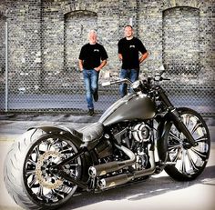 two men standing next to a black motorcycle