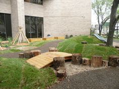 a wooden bench sitting in the middle of a lush green park next to a building