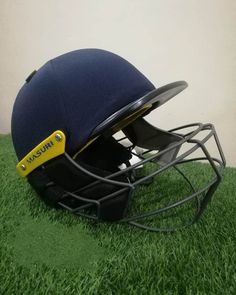 a helmet sitting on top of a green grass covered field next to a white wall