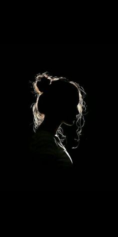 the silhouette of a woman's head against a black background, with her hair blowing in the wind