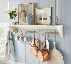 there are pots and pans hanging on the shelf above the kitchen utensils