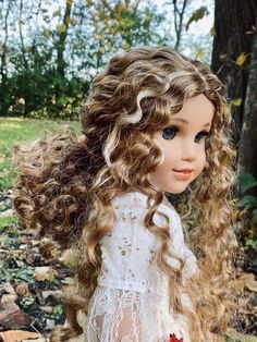 a close up of a doll with curly hair and blue eyes wearing a white dress