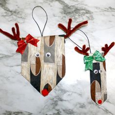 two wooden reindeer ornaments with red bows on their heads and noses, hanging from the ceiling