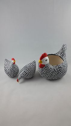 two ceramic chickens sitting next to each other on a gray surface with white and black designs