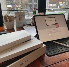 an open laptop computer sitting on top of a wooden desk next to boxes and papers