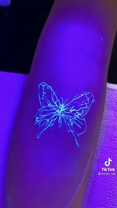 a blue glow tattoo on the arm of a person's arm with a butterfly drawn on it