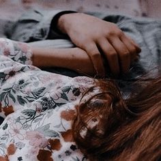 a woman laying on top of a bed next to a pillow covered in floral sheets