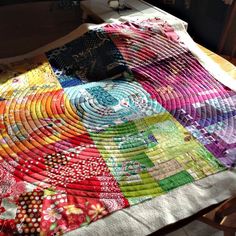 a colorful quilt sitting on top of a wooden table