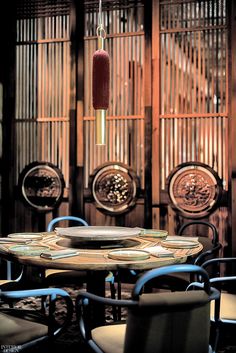 a round table with chairs around it in front of bamboo screens and wall hangings