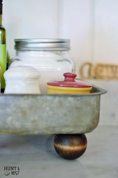 a metal tray with jars on top of it and a wooden ball in the middle