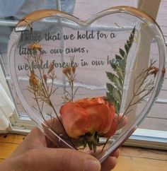 someone is holding up a heart shaped vase with flowers in it that says those that we hold for a friend are our arms, we will forever in our hearts