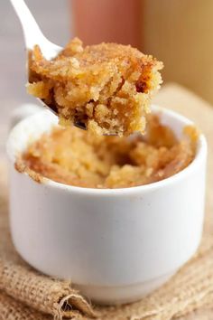 a close up of a spoon with food in it on a table next to a cup