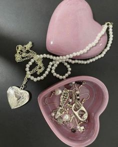 a pink heart shaped object with pearls and other jewelry items on it's side