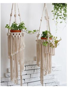 two macrame planters with plants in them hanging from the side of a brick wall