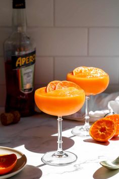 two orange margaritas sitting on top of a table