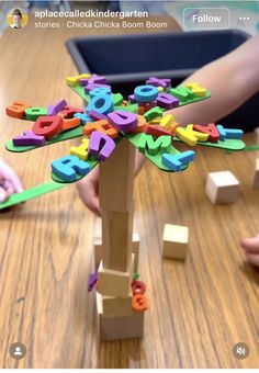 children are playing with letters and numbers on a wooden table in front of an ipad