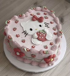 a hello kitty cake on a white plate with pink icing and red flower decorations