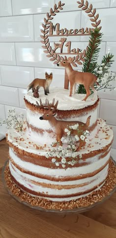 a three tiered cake with white frosting and deer figurines on top