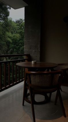 a wooden table sitting on top of a balcony next to a tall tree filled forest