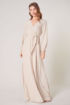 Warm and inviting, the Wholehearted Maxi Dress is a perfect combination of modest and sultry. Long balloon sleeves frame a surplice neckline separated by a tie at the waist, creating a forgiving faux wrap. The skirt maintains an airy and flowy shape that trails behind as you walk down the aisle. - Chiffon- Faux wrap- Keyhole- Elastic waist- Comes in 14 ColorsSize + Fit - Model is 5'9" and wearing size XS- Measurements taken from size S - Chest: 35"- Length: 63 1/4" Fabric Self: 100% PolyesterLin Elegant V-neck Dress With Surplice Neckline For Fall, Elegant V-neck Faux Wrap Dress, Fall V-neck Belted Maxi Dress, Chic Solid Color Long Sleeve Wrap Dress, V-neck Wrap Dress With Tie Waist For Brunch, Fall Maxi Wrap Dress For Brunch, Chic Fall Maxi Wrap Dress, Fall Maxi Dress With Surplice Neckline For Date Night, Long Sleeve Faux Wrap Dress For Date Night