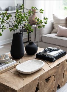 a living room with a couch, coffee table and vases on top of it