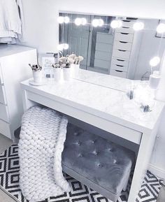 a white vanity with lights on it and a bench in front of the counter top