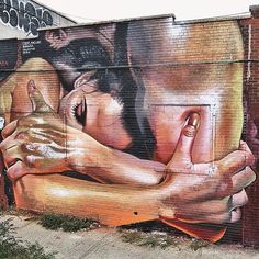 a large mural on the side of a building with two people hugging each other and holding hands