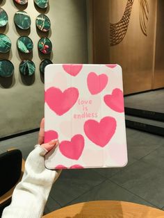 a person holding up a book with hearts on it